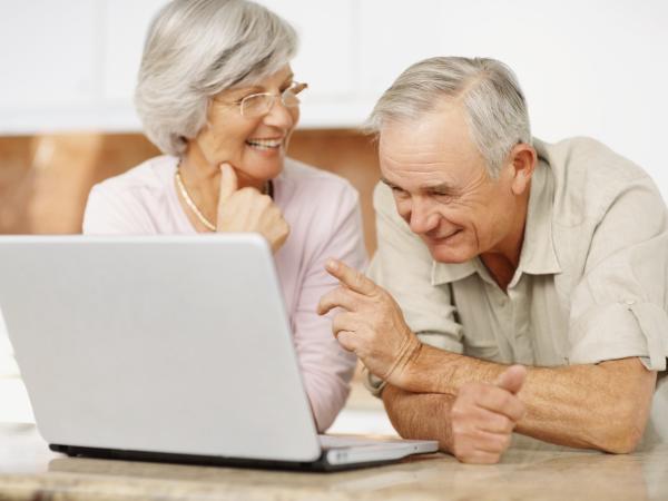Zwei Senioren nutzen zuhause einen Laptop