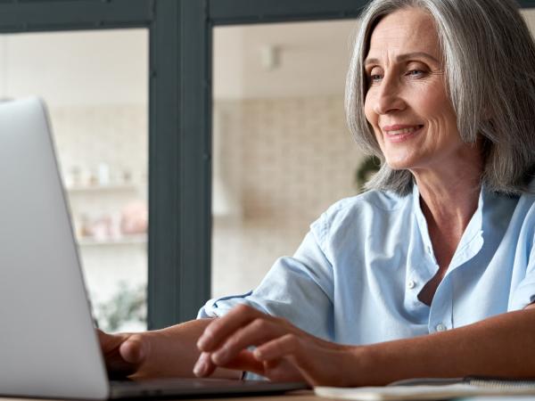 Ältere Dame verfolgt eine Online-Veranstaltung am Laptop