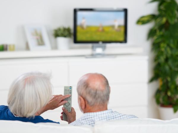 Zwei Senioren nutzen eine Fernbedienung für das TV-Gerät