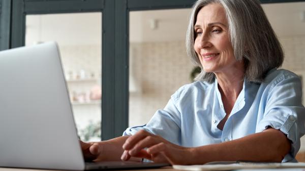 Ältere Dame verfolgt eine Online-Veranstaltung am Laptop